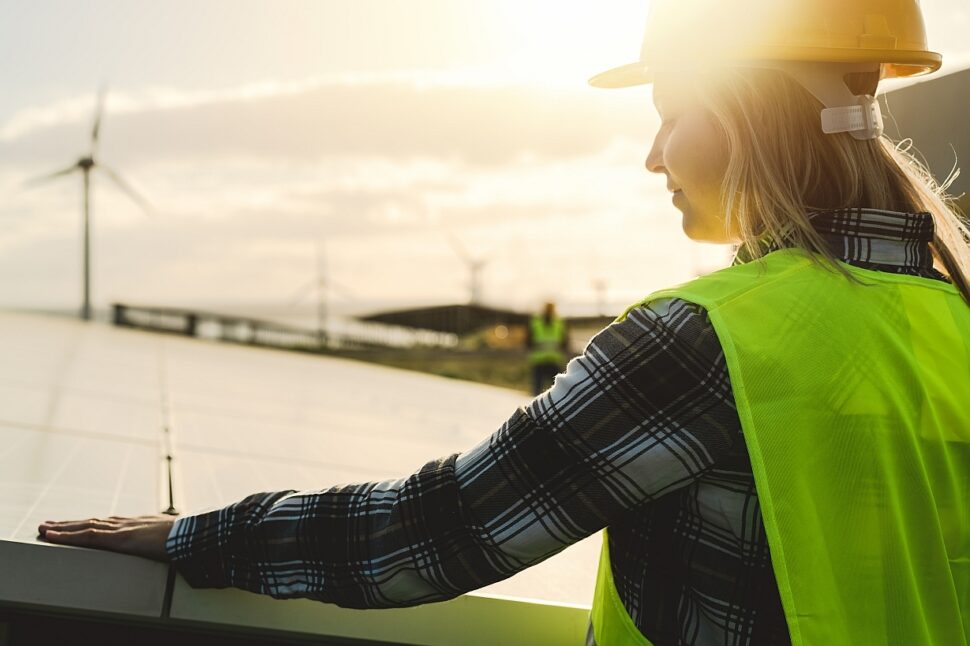 A woman worker checking solar panels at sunset