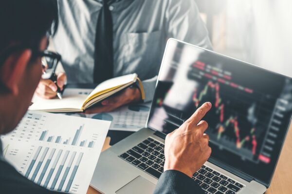 Hand using tablet with financial graphs and reports